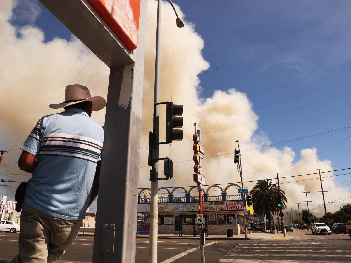 A Boyle Heights resident look at the smoke from a fire at a warehouse.