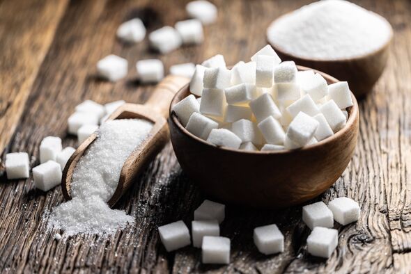 Granulated sugar in a wooden scoop or bowl on an old oak table. Granulated sugar in a wooden scoop or bowl on an old oak table.