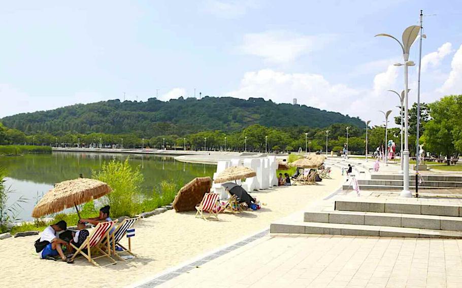 People using a parasol by the pond of a park in Seoul, Korea.
