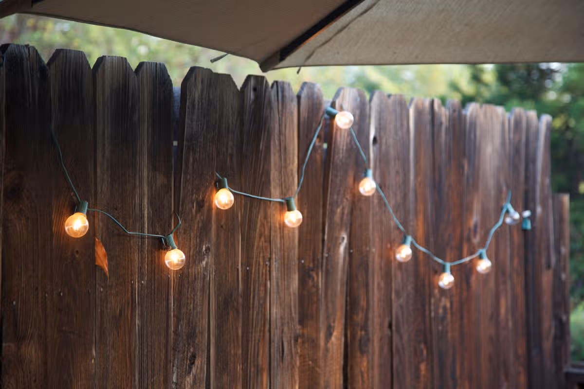 Clear lights hang along a wooden fence