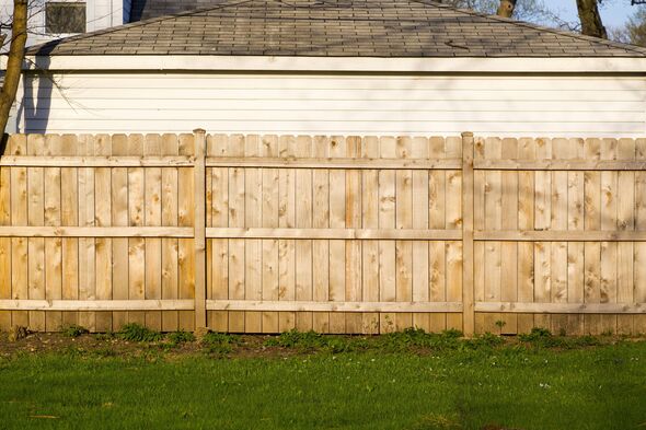 A hard wood fence outside a house A hard wood fence outside a house
