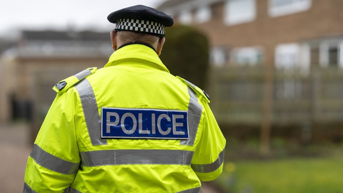 A policeman walking away from an elderly person's home. - stock photo