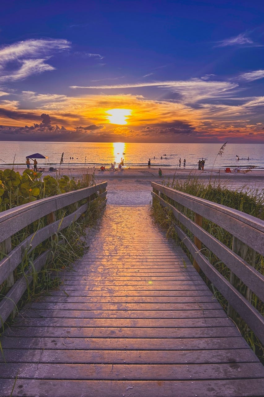 sunset view over the beach with a wooden walkway leading to the shore