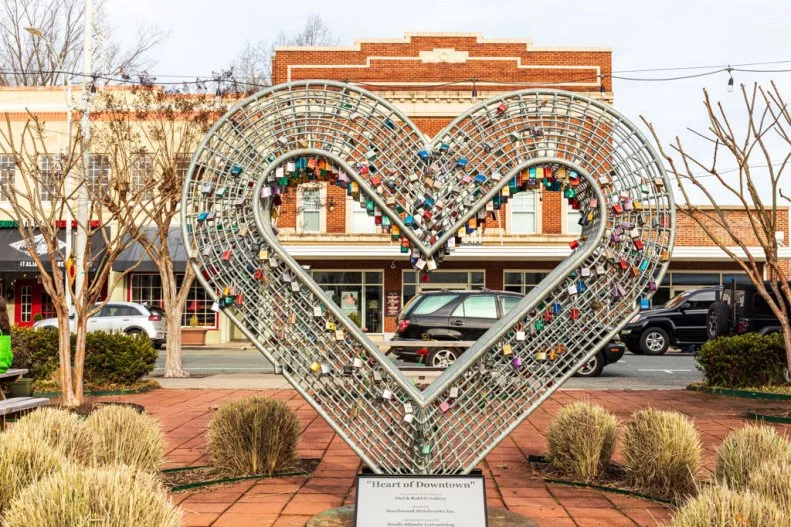 2247641033 BURLINGTON, NC, USA-2 JAN 2023: The Paramount Theater setting behind a steel heart sculpture filled with engraved locks.