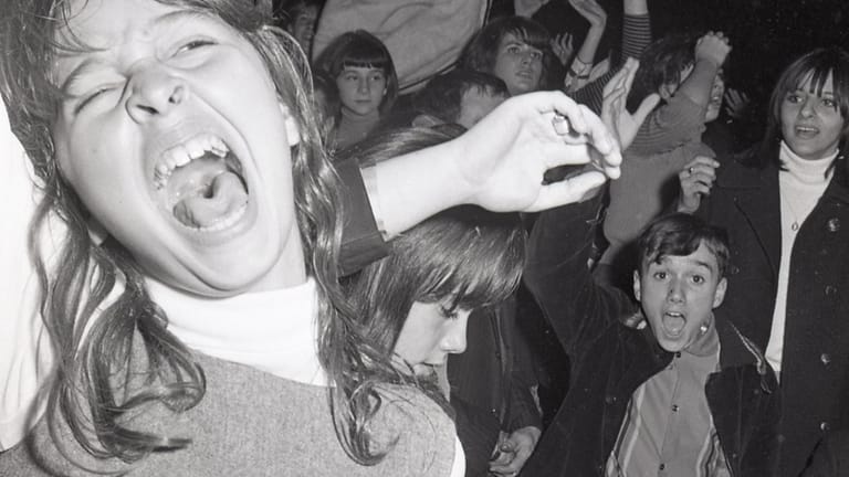 Fans scream and cheer for the English musical group Dave...