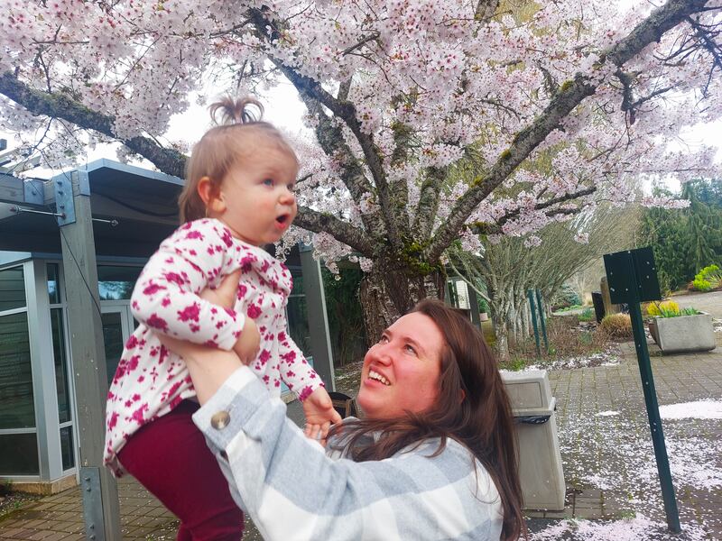 Olivia is shown lifting Khloe underneath a blossoming cherry tree